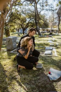 couple at graveside sobbing