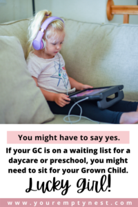 toddler sitting on the couch with headphones on and reader in her lap